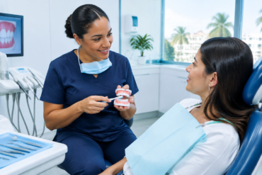 Profesional odontológico explica a una paciente el cuidado y la frecuencia de la limpieza dental.